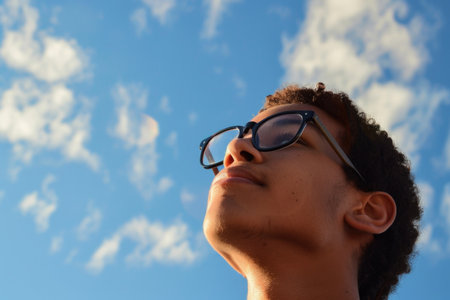 A young man in sunglasses gazes up at the sky with a sense of wonder and contemplation.の素材