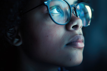 A close-up portrait of a young person wearing glasses, gazing intently with a thoughtful expression.の素材