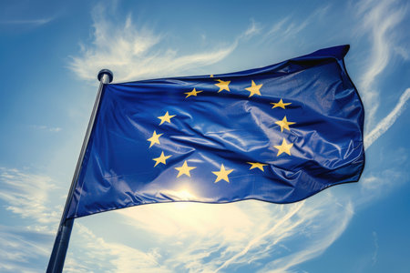 A vibrant depiction of the European Union flag waving high in the sky, under the warmth of the sun.の素材