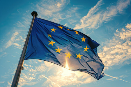 A vibrant depiction of the European Union flag flying high in the sky on a standard flagpole.の素材
