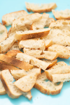 A pile of bread crumbs on a blue background. The crumbs are scattered and unevenly sized, giving the impression of a messy and disorganized scene. Scene is somewhat chaotic and unkemptの写真素材