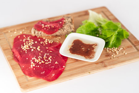 A plate of meat and bread with a sauce on a wooden cutting board. Scene is casual and inviting, as it looks like a simple and delicious mealの写真素材