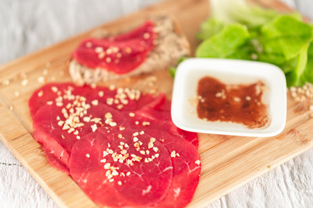 A plate of meat with nuts and a white bowl of sauce. Scene is casual and inviting, as it looks like a delicious meal to share with friends or familyの写真素材