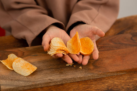 A close view of a hand picking a chip from a spread of chips on a table.