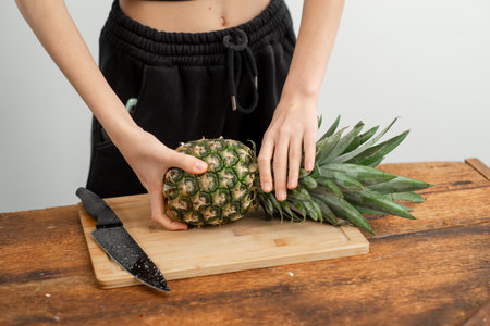 Organic pineapple held firmly, ready for healthy recipes, on wood.の写真素材