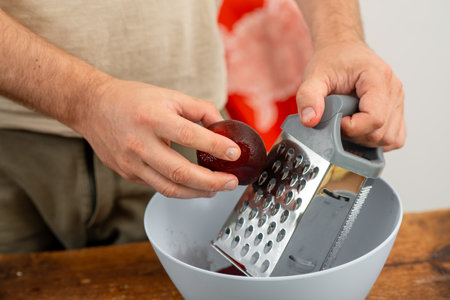 Making beet salad: hands with red beet juice using a metal grater.の写真素材