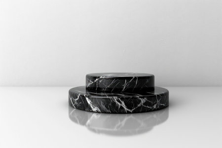A two-tiered black marble platform sits on a white surface, creating a minimalist and elegant display for products or objects.の素材