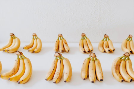 Rows of Fresh Ripe Bananas Against a White Background - Minimalistic Fruit Photography.の素材