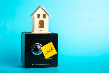 Miniature house on safe with lock note: concept of security and home protection.の写真素材