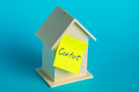 Cozy wooden house model with comfort note on blue background.