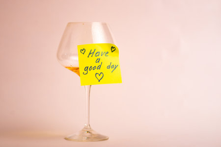 Elegant wine glass with positive message on a sticky note for an uplifting day.