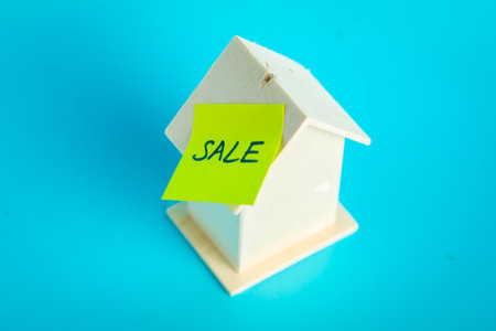 Wooden house model with sale note on blue background for real estate concepts.の写真素材