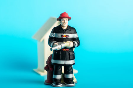 Firefighter figurine with hydrant and house against blue background.の写真素材