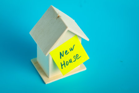 New house concept: small wooden model with sticky note on blue background.の写真素材