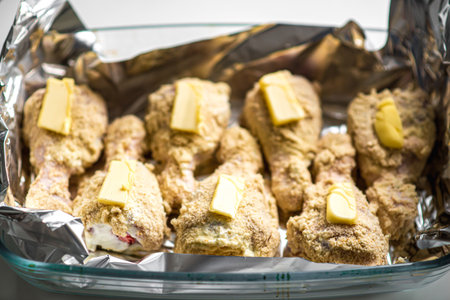 Delicious homemade breaded drumsticks with butter in baking dish.の写真素材