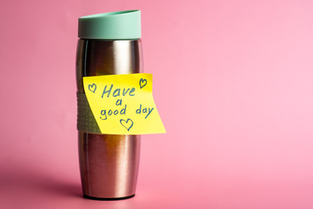 Reusable coffee cup with inspiring message on pink background.の写真素材