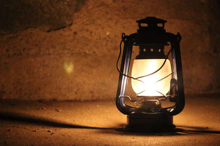 Kerosene lamp lights in a dark near a stone wallの写真素材
