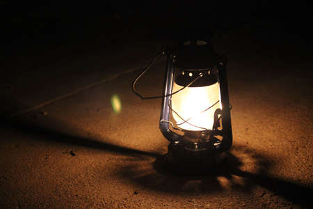 Kerosene lamp lights in a dark near a stone wallの写真素材