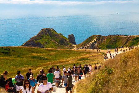 Dorset, United Kingdom- July 14, 2018: People walking on the path that leads to Durdle Door. Durdle Door is a natural limestone arch on the Jurassic Coast near Lulworth in Dorset, England.のeditorial素材