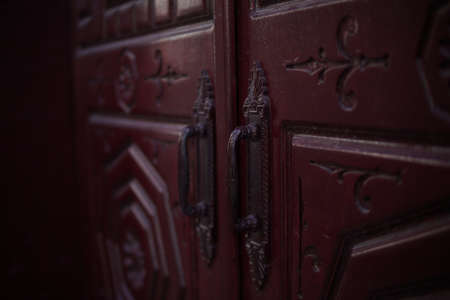 Old wooden door with metal handles and wrought-iron elements. Close-up.の写真素材