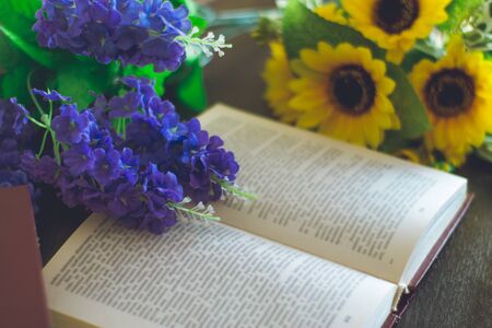 Opened book with flowers on a wood table.の写真素材
