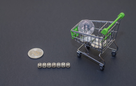 Shop trolley for purchases with bitcoins. Crypto currency bitcoin on a black background. Empty space for text.の写真素材