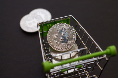 Shop trolley for purchases with bitcoins. Crypto currency bitcoin on a black background. Empty space for text.の写真素材