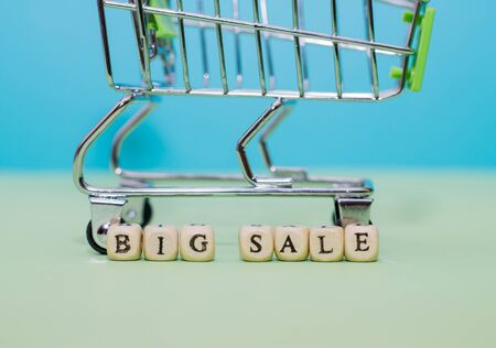 Shopping trolley and word big sale from cubes on a green background.の写真素材