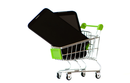 Shopping cart with mobil phone on a isolated background. Smartphone in shop trolley.の写真素材