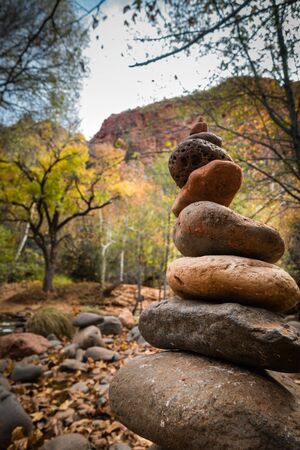 Stacked cobblestones in tranquil and zen-like nature surroundings with mountains and trees in Sedona, Arizona near famous Cathedral rock vortex. No people, daylight.の写真素材