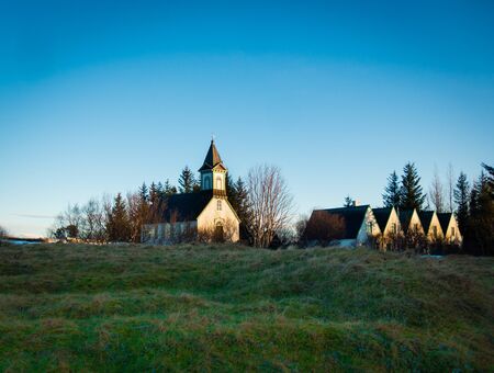 Old christian church and traditional guesthouses in historic Thingvellir national park. Sunny day with clear blue sky. No people visible, copyspace.の写真素材