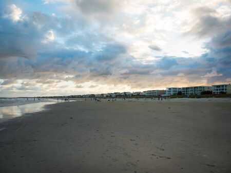 Dramatic cloudscape with sun setting above lively Tybee island beach, Georgia. Colorful clouds with almost empty beach.の写真素材