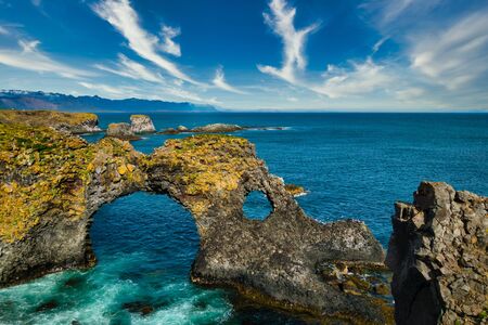 Gatklettur rock formations on Snaefellsnes peninsula and atlantic ocean on sunny day. Beautiful blue water and clear blue sky. No people visible, copyspaceの写真素材