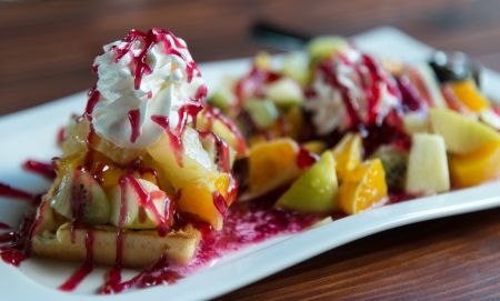 fruit salad with whipped cream topping and wild berry sauceの写真素材