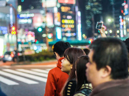 Tokyo, Japan - March 2018: People looking at the neon city lights of Tokyo