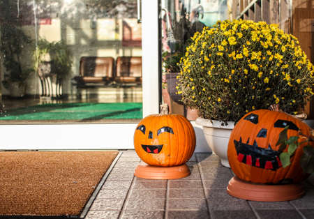 Two Halloween pumpkins with faces at the entrance to a businessの写真素材