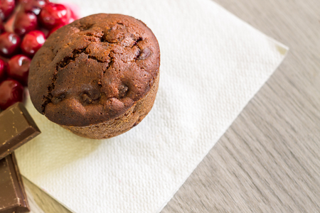 Chocolate muffin with sour cherries on white napkin. Top view with copy spaceの写真素材