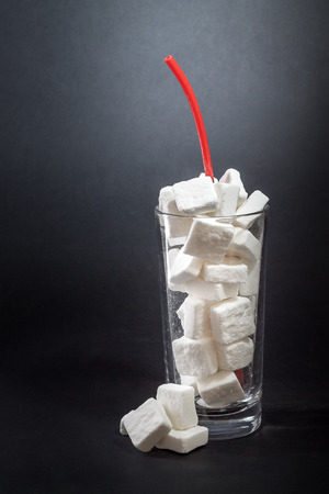 Glass full of sugar cubes with straw. Concept of unhealthy drinks. Copy spaceの写真素材
