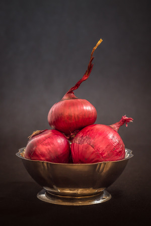 Red onions in metallic bowl on black background. Copy spaceの写真素材