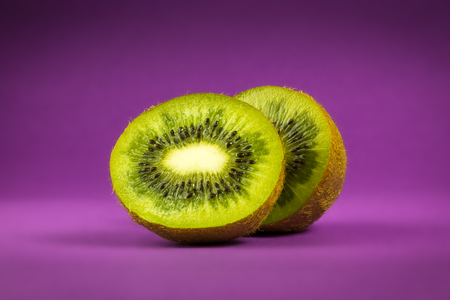Kiwi fruit on purple background sliced in half