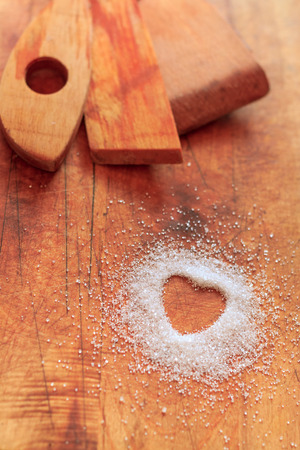 Heart-shaped sugar on cutting board with wooden utensils. I love cooking concept.の写真素材