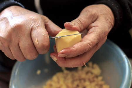 Closeup of old man's hands while he is slicing potatoesの写真素材