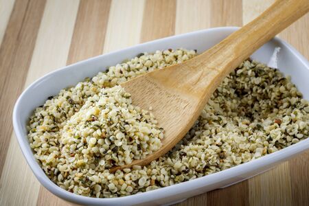 Hemp seeds in wooden spoon in white bowlの写真素材