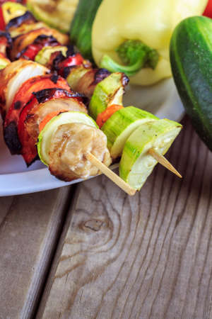 Grilled chicken and vegetables on wooden skewers on wooden background. Copy spaceの写真素材