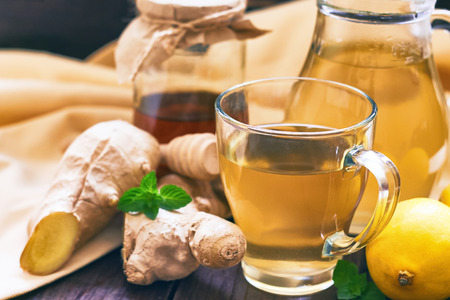 Ginger tea served with honey, lemon and mint on wooden table