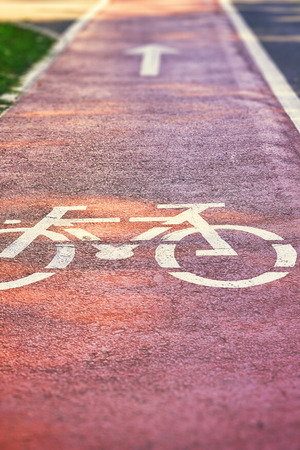 Red bike lane on sidewalk with painted white bicycle and arrow signs. Copy spaceの写真素材