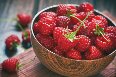 Fresh raspberries in wooden bowl on wooden backgroundの写真素材