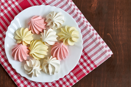 Fresh delicious colored meringue cookies served on white plate. Top view with copy spaceの写真素材