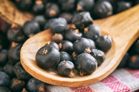 Close-up of dried juniper berries in wooden spoonの写真素材