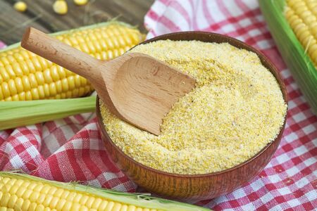 Organic maize flour in wooden bowl with fresh cornの写真素材